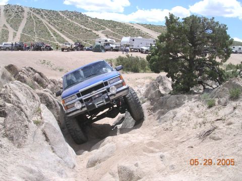 1994 Ford Bronco - Off-road truck tackling a challenging rocky trail with other vehicles and campers nearby.