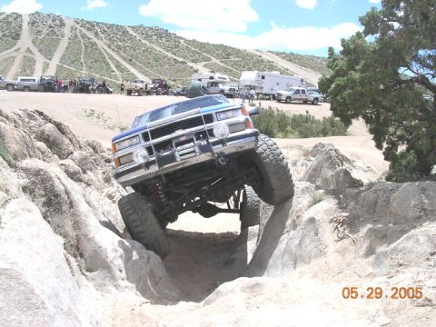 1994 Ford Bronco - A modified truck navigates a rocky obstacle course with spectators and other vehicles present.