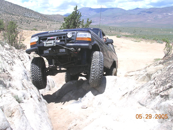 Dark Ford Bronco with winch and lift climbing rocks on a desert trail