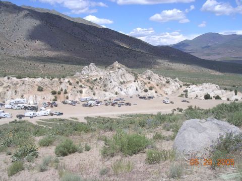 1994 Ford Bronco - A collection of vehicles and RVs are parked in a dry, rocky area with mountains in the background.