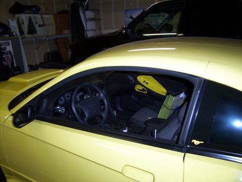 2002 Ford Mustang - Interior view of a yellow coupe, parked in a garage with another vehicle behind it.