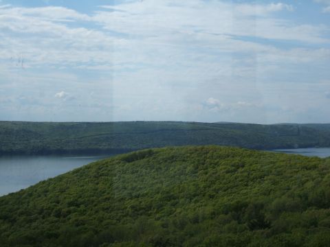 1998 Ford Taurus - A scenic view of rolling green hills and a calm lake on a partly cloudy day.