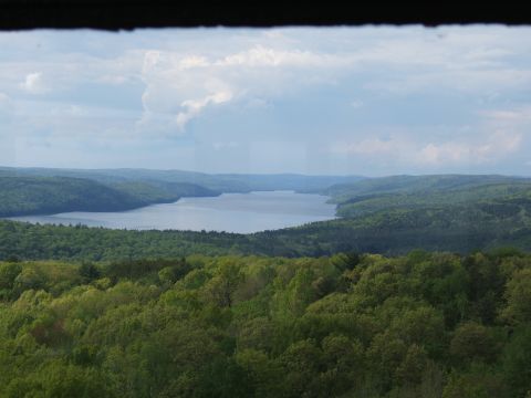1998 Ford Taurus - A picturesque view of a lake among lush green hills and trees, under a dramatic cloudy sky.