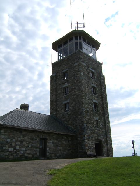 1998 Ford Taurus - A stone observation tower with a distinctive glass-enclosed upper level stands against a cloudy sky, with a smaller stone building to its l…
