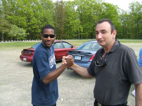1998 Ford Taurus - Two men shake hands in front of two sedans, one red and one blue, with a 1998 Ford Taurus visible.