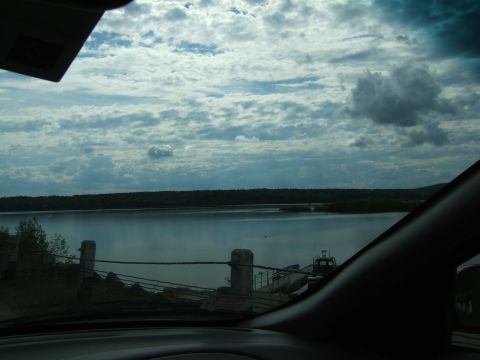 1998 Ford Taurus - View from inside a vehicle shows a lake with a ferry and cloudy skies.