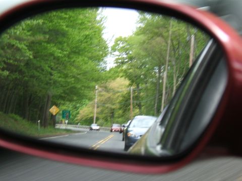 1998 Ford Taurus - Reflection in the side mirror captures a scenic drive with other vehicles on the road.