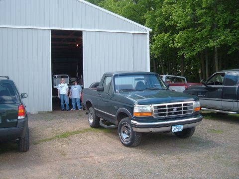 1994 Ford Bronco - A dark green Ford Bronco is parked in front of a barn with two people standing in the doorway.