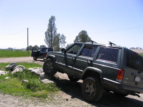 2000 Jeep Cherokee - Two SUVs are seen off-roading on a sunny day with a clear blue sky.