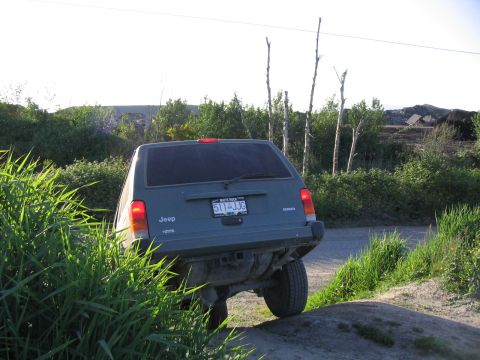 2000 Jeep Cherokee - This Jeep Cherokee is navigating a dirt path with tall grass on the side.