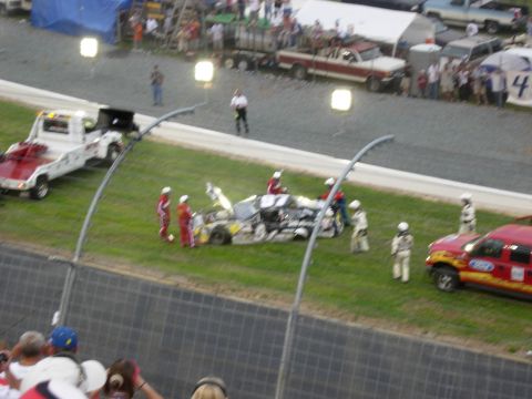 1995 Ford Bronco - Race car scene with crew members and tow truck on the grass at a track.