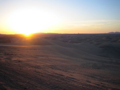 1968 Ford Mustang - A vast expanse of desert dunes stretches towards the horizon under a warm sunset sky.