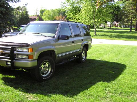 2000 Chevrolet Tahoe - A silver Chevrolet Tahoe SUV is parked on a green lawn with trees in the background.