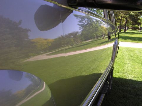 2000 Chevrolet Tahoe - Side view of a vehicle showing reflections of a park-like setting.