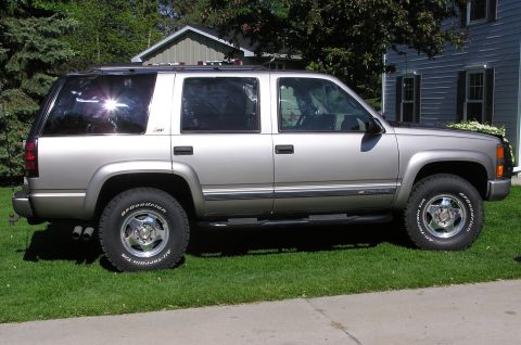 2000 Chevrolet Tahoe - This silver 2000 Chevrolet Tahoe is seen from the side, parked on a grassy lawn in front of a house.