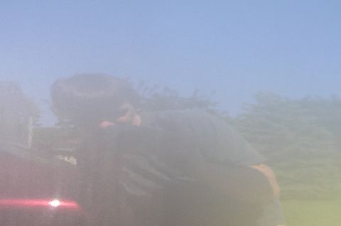 2000 Chevrolet Tahoe - Reflection of a person in the side door of a red vehicle.