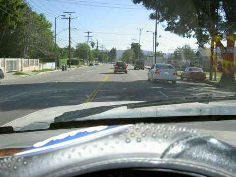 1988 Ford Bronco - View from inside a vehicle driving down a residential street on a sunny day.
