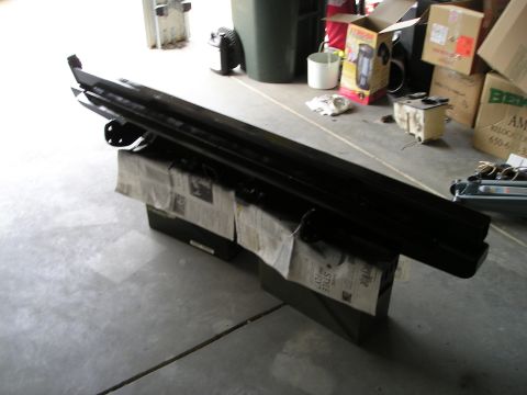1996 Ford Bronco - Two black custom bumpers are displayed on top of boxes covered with newspaper, likely in a garage or workshop setting.