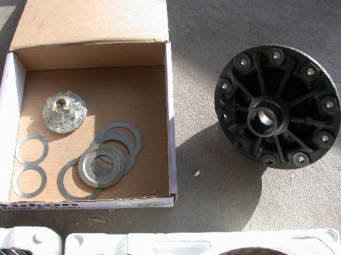 1994 Ford Bronco - Differential carrier and shims are laid out on a concrete surface next to an open cardboard box.