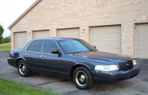 1998 Ford Crown Victoria - This sedan is parked in front of a residential garage. The vehicle's body style suggests a model year later than 1998.