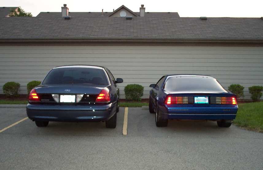 Rear view of a Ford Crown Victoria and a blue Ford Mustang parked side by side