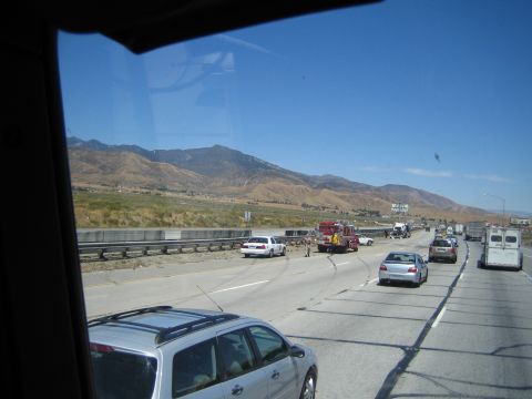 1990 Ford Bronco - Seen through a vehicle window, a fire truck and stopped cars gather at a freeway incident below arid mountains.