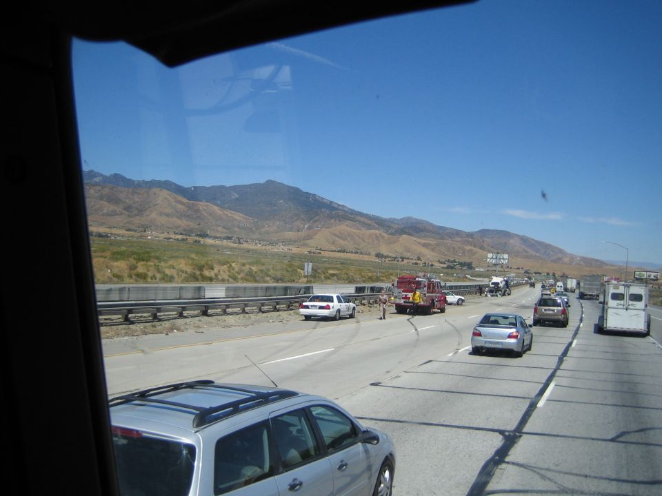 View through a window of a freeway accident scene with a fire truck and cars near desert mountains