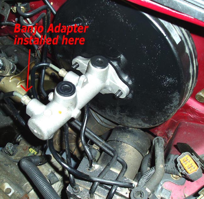 Brake master cylinder on booster with red arrow labeled Banjo Adapter installed here
