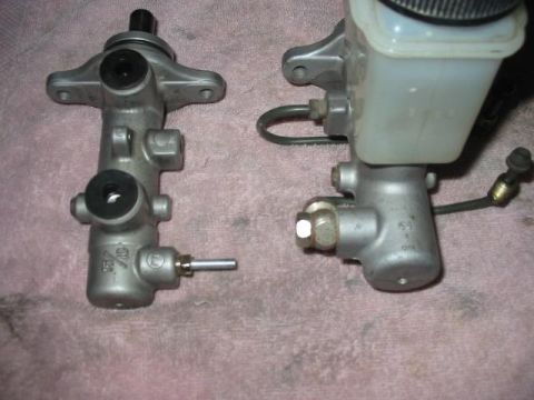1995 Ford Probe - Two brake master cylinders are shown side-by-side on a textured surface.