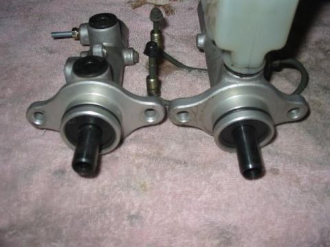 1995 Ford Probe - Two brake master cylinders are shown, one with a plastic reservoir and the other without.
