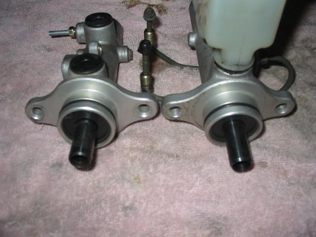 Two brake master cylinders side by side comparing bore sizes, one with fluid reservoir
