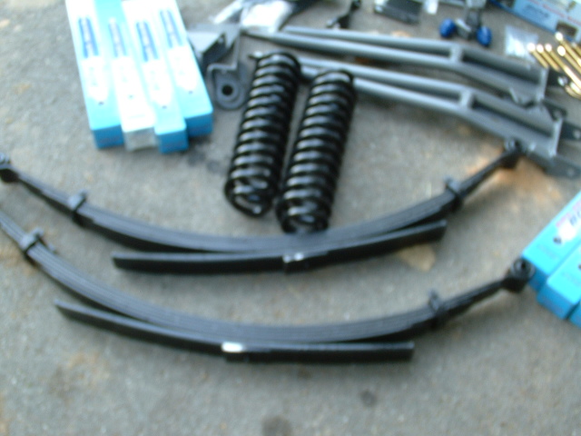 Suspension parts on pavement: black coil springs, leaf springs, radius arms, and boxed shocks