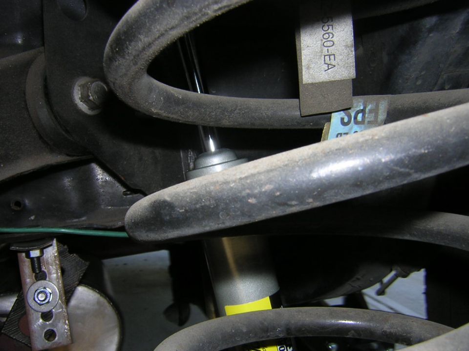 Coil spring and shock absorber under a car, with part tag reading 5560-EA on the coil