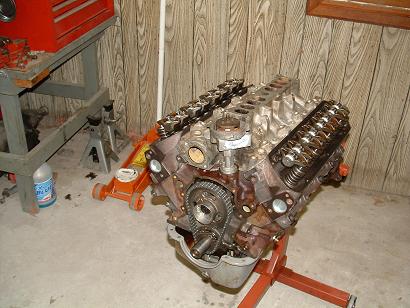 1985 Ford LTD Crown Victoria - An engine is mounted on a stand in a garage, with tools and equipment in the background.
