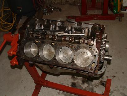 1985 Ford LTD Crown Victoria - The engine block is disassembled and mounted on an engine stand in a garage setting.