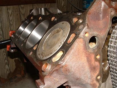 1985 Ford LTD Crown Victoria - Close-up of an engine block, showing cylinders and rusty metal components.