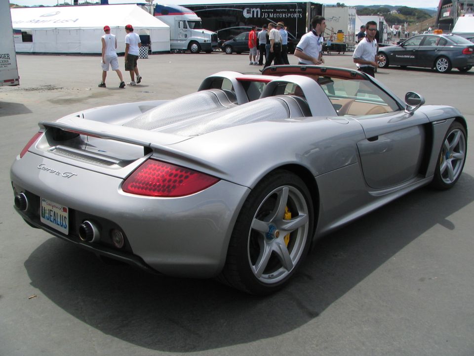 Silver Porsche Carrera GT rear view with 'UJEALUS' plate at a race paddock