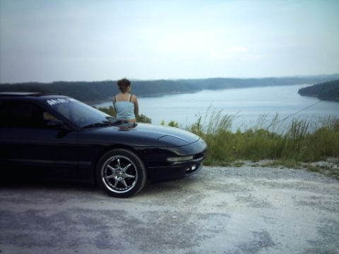 1995 Ford Probe - A 1995 Ford Probe is parked at an overlook with a woman sitting on its hood.