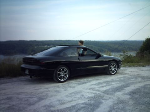 1995 Ford Probe - A black 1995 Ford Probe is parked on a gravel road with a scenic overlook in the background.