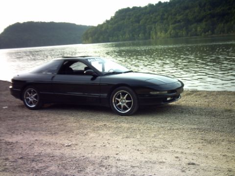 1995 Ford Probe - A black 1995 Ford Probe sits by the water's edge on a sunny day.