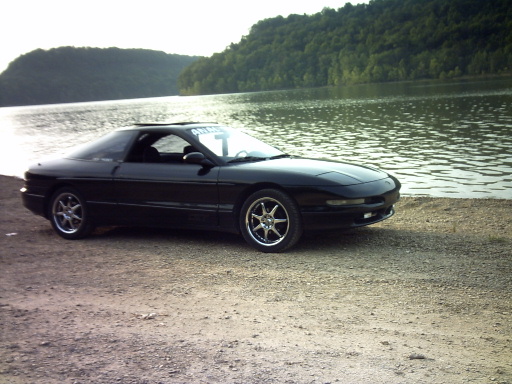 1995 Ford Probe parked on gravel near a lake with trees in the background