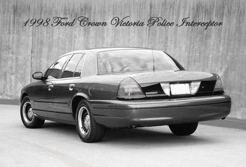 Rear three-quarter view of a 1998 Ford Crown Victoria Police Interceptor sedan, black-and-white photo with text overlay.