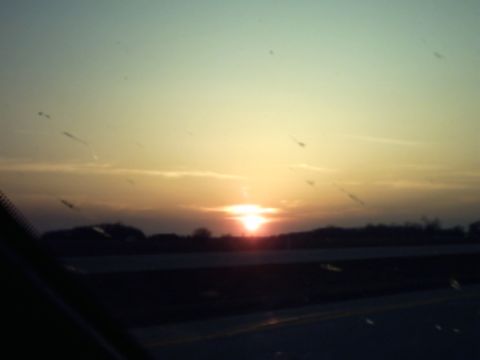 1995 Ford Probe - A sunset scene is captured from inside a vehicle, with the sun low on the horizon.