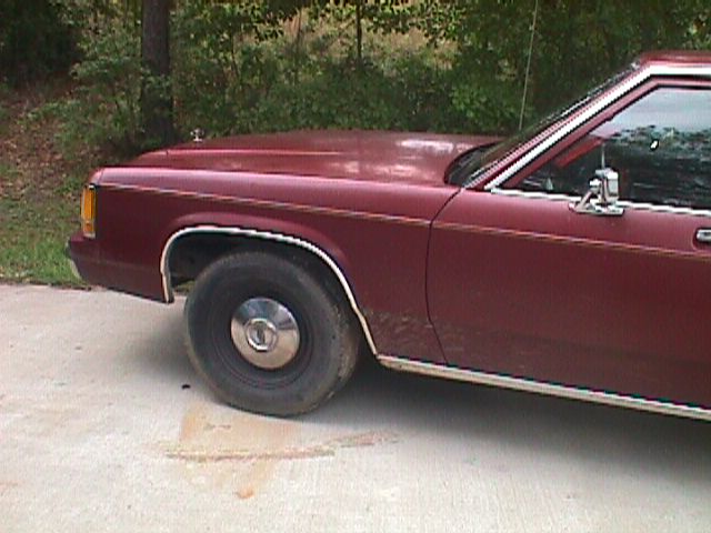 Maroon sedan, side view, showing front fender and door. Chrome trim along the bottom and window line