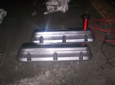 1989 Ford Bronco II - Two aluminum valve covers are shown on a concrete surface, with a red oil cap on the upper one.
