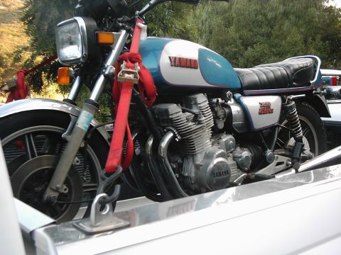 1978 Ford Bronco - A blue and white Yamaha motorcycle is secured with red straps to a trailer.