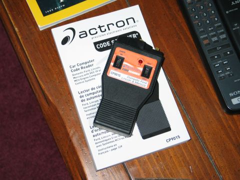 1995 Ford Bronco - Actron CP9015 code scanner and manual on a wooden table with remote controls.
