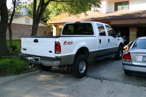 2004 Ford F-350 - A white Ford F-350 pickup truck is parked in a driveway next to another vehicle.