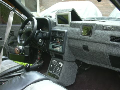 1991 Ford Festiva - The interior features a fuzzy grey dashboard with an aftermarket screen and a 'Festiva' badge visible.