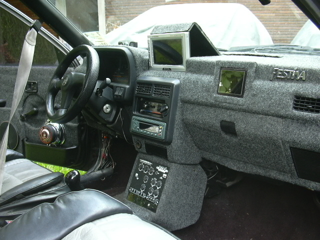 Ford Festiva interior with carpeted custom dash, flip-up LCD screen, and aftermarket stereo console